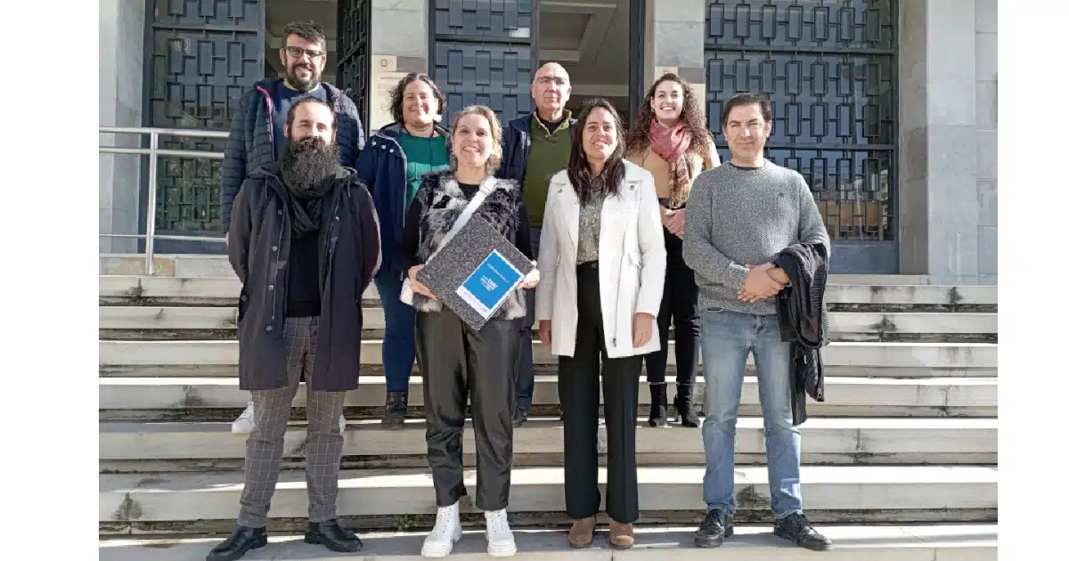 Grupo de pessoas sorridentes em frente a edifício.