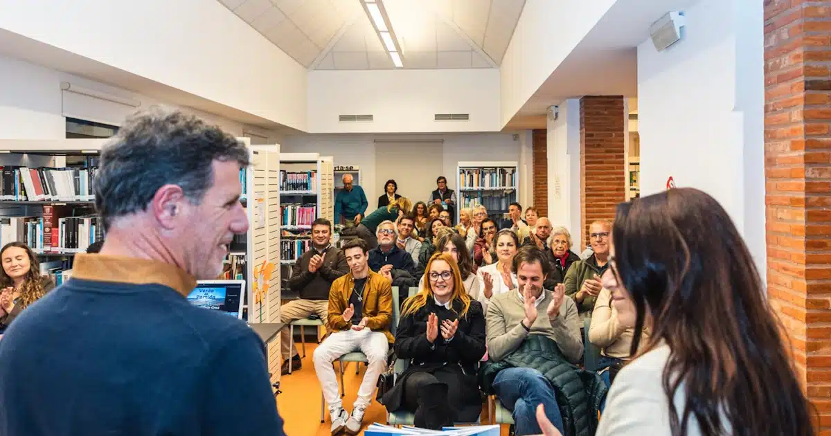 Público aplaudindo em evento cultural numa biblioteca.